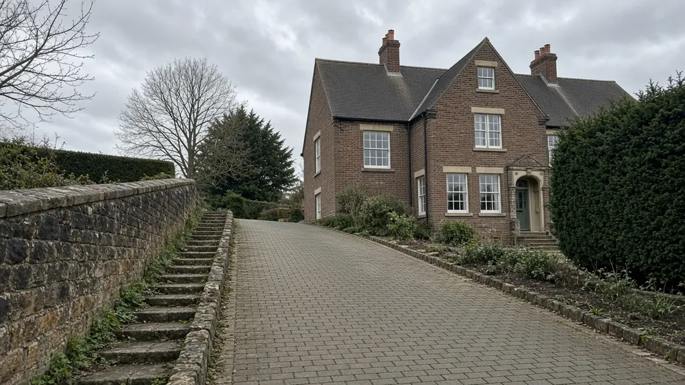 Example image: a sloping block paved driveway with a stone retaining wall